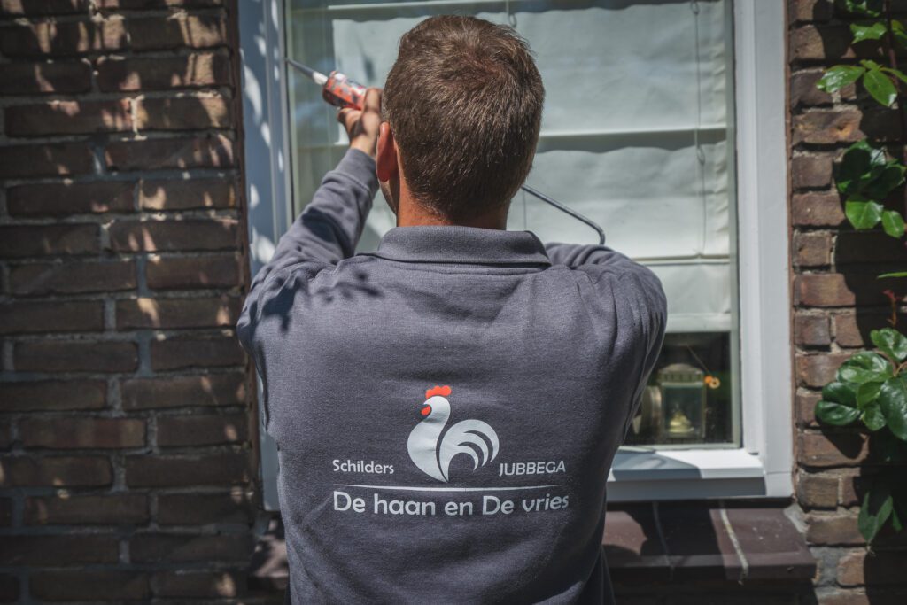 Schilder van De Haan en De Vries werkt aan een buitengevel