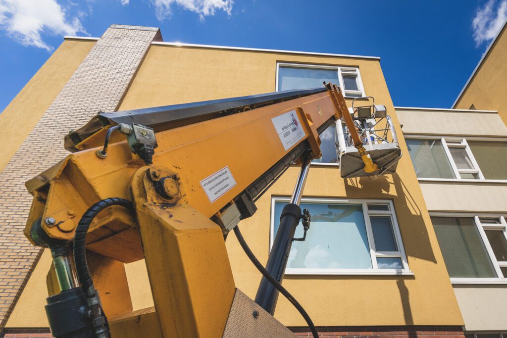 Onderhoud aan appartementencomplex vanuit een hoogwerker
