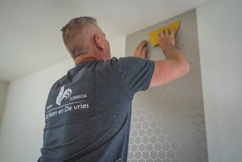 Schilder brengt behang aan op een binnenwand